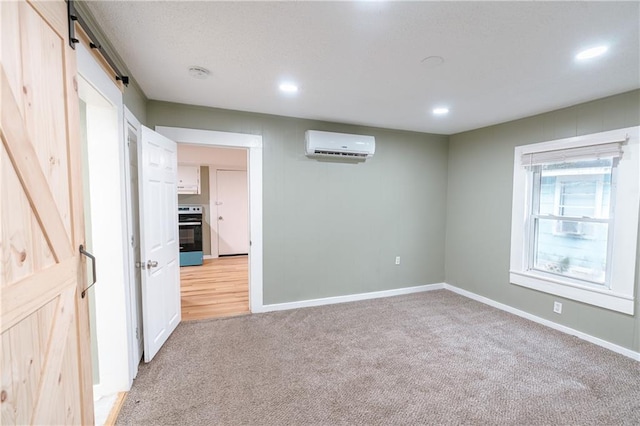 carpeted empty room with a barn door and a wall mounted air conditioner