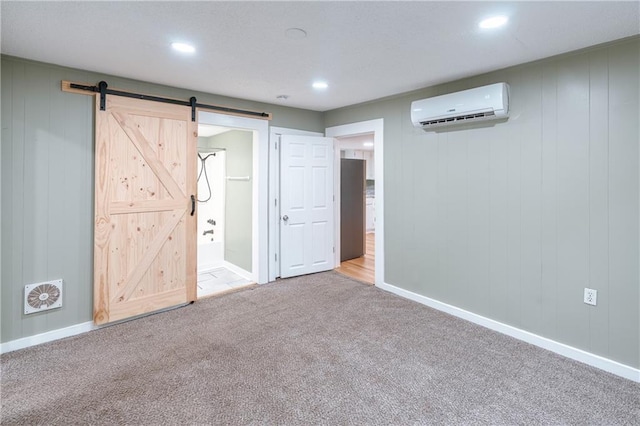 interior space with an AC wall unit, wooden walls, a barn door, and light carpet