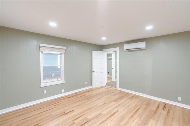 empty room featuring wood walls, a wall unit AC, and light hardwood / wood-style flooring