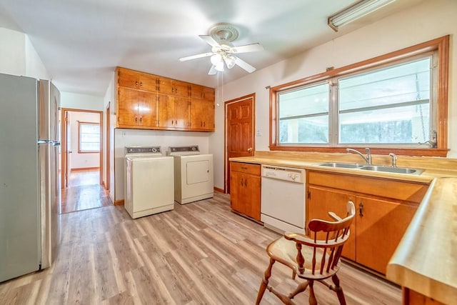 kitchen with sink, washer and clothes dryer, stainless steel fridge, dishwasher, and light wood-type flooring