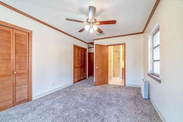 unfurnished bedroom with crown molding, ensuite bath, carpet floors, and two closets