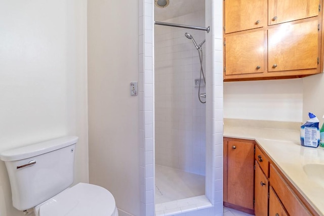 bathroom featuring a tile shower, vanity, and toilet