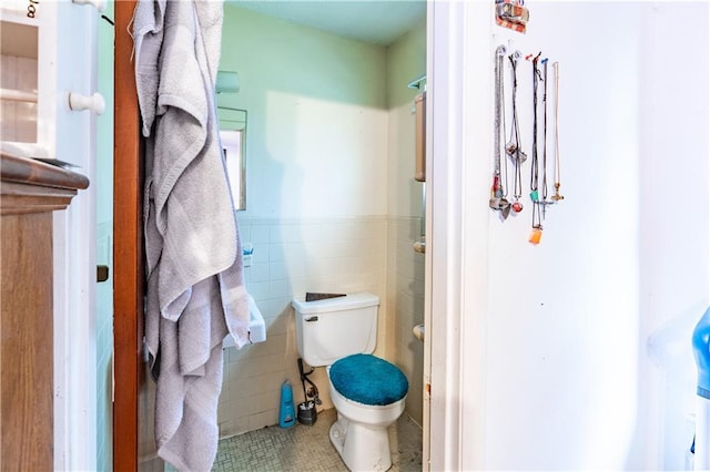 bathroom with tile patterned flooring, toilet, and tile walls