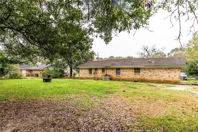 back of house with central AC unit and a yard