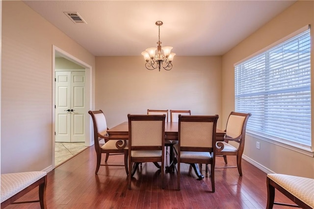 dining area featuring hardwood / wood-style floors, a healthy amount of sunlight, and an inviting chandelier