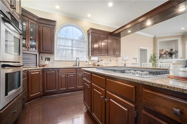 kitchen featuring a sink, backsplash, stainless steel appliances, and ornamental molding