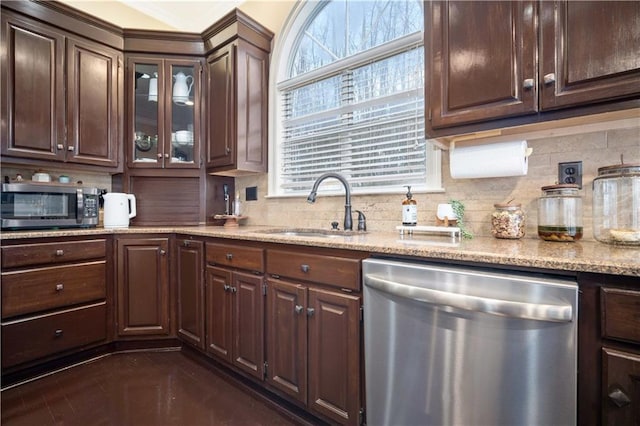 kitchen with dark brown cabinetry, backsplash, stainless steel appliances, and a sink