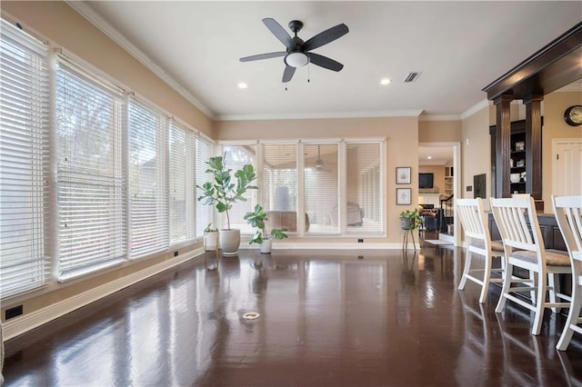 interior space with wood finished floors, visible vents, baseboards, ceiling fan, and ornamental molding