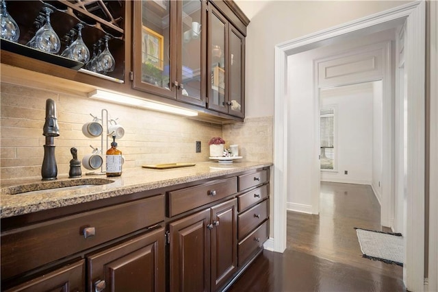 bar featuring tasteful backsplash, dark wood-type flooring, baseboards, and a sink