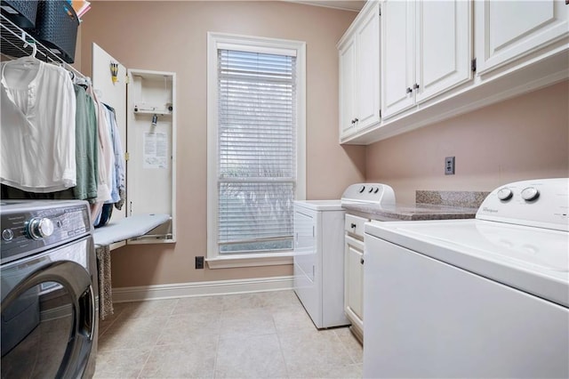 laundry room with cabinet space, light tile patterned flooring, separate washer and dryer, and baseboards