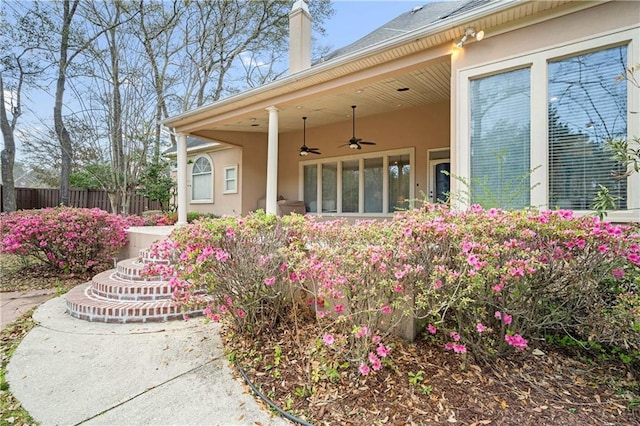 exterior space with stucco siding, a ceiling fan, and fence