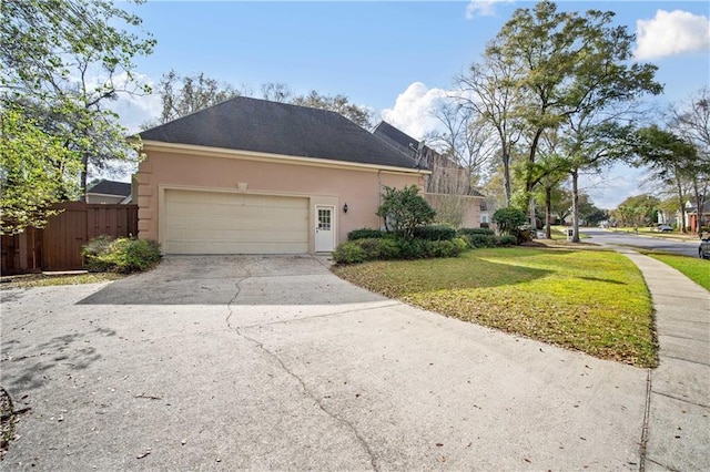 view of property exterior with fence, concrete driveway, stucco siding, a yard, and an attached garage