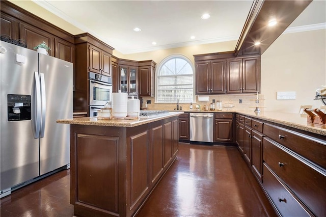 kitchen with ornamental molding, backsplash, stainless steel appliances, dark brown cabinetry, and light stone countertops