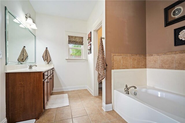 bathroom featuring a garden tub, vanity, tile patterned flooring, and baseboards