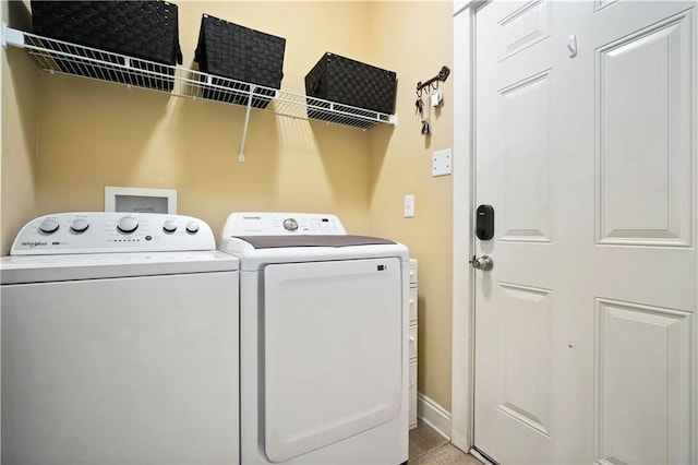 laundry room with light tile patterned flooring, washing machine and clothes dryer, laundry area, and baseboards