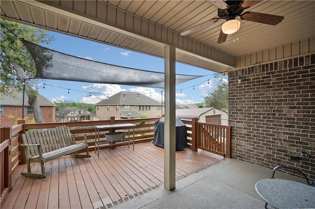 wooden terrace with ceiling fan, an outbuilding, area for grilling, a residential view, and a shed
