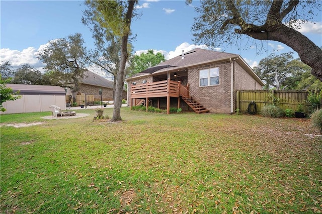 back of property with a wooden deck, a lawn, stairs, a fire pit, and fence