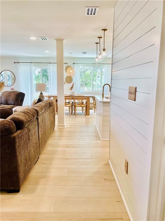 2026 Norman Ln, Gulf Shores, AL 36542 - hallway featuring wooden walls, visible vents, light wood-style flooring, and a healthy amount of sunlight
