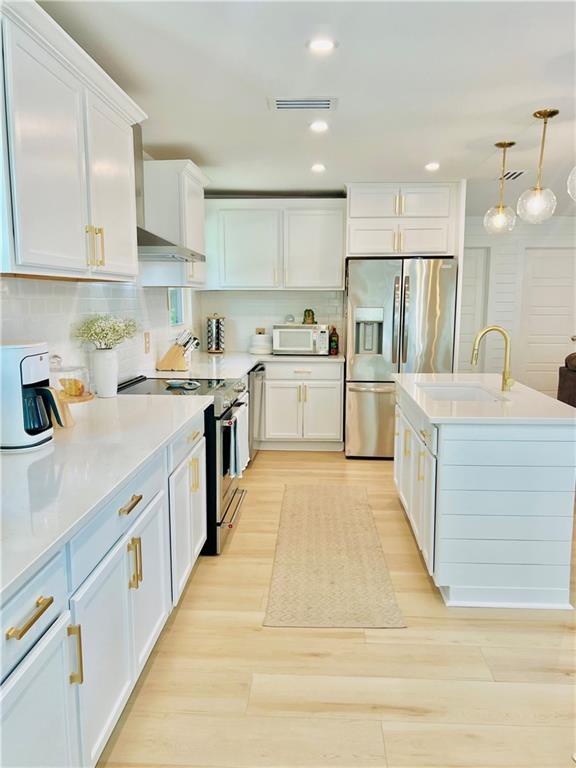 2026 Norman Ln, Gulf Shores, AL 36542 - kitchen featuring tasteful backsplash, a sink, light wood-type flooring, white cabinetry, and stainless steel appliances