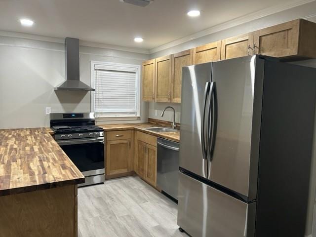 kitchen with wooden counters, wall chimney exhaust hood, sink, ornamental molding, and stainless steel appliances