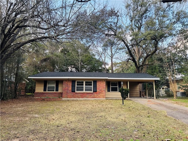 ranch-style house featuring a carport, cooling unit, and a front lawn