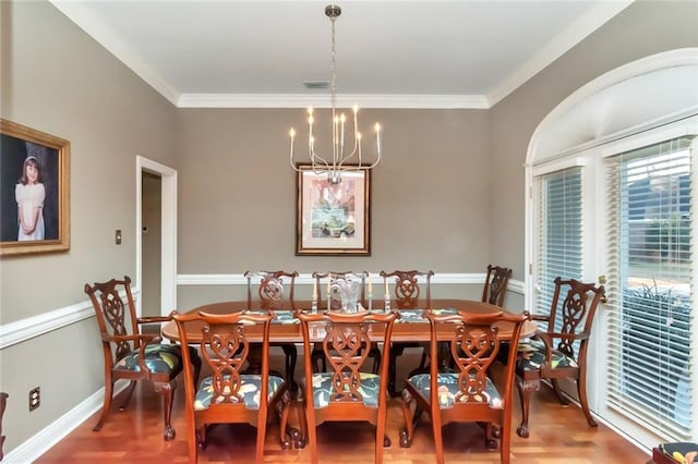 dining area with crown molding, hardwood / wood-style flooring, and a notable chandelier