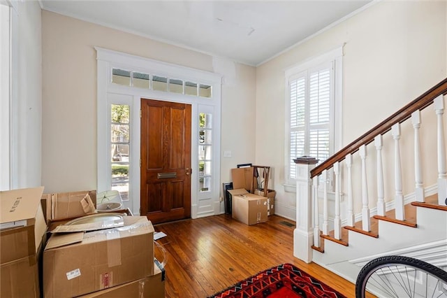 foyer featuring crown molding, hardwood / wood-style floors, and a healthy amount of sunlight