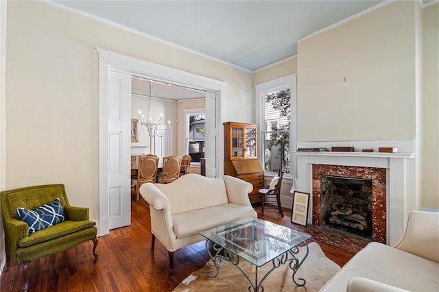 living area featuring a fireplace, hardwood / wood-style floors, ornamental molding, and an inviting chandelier