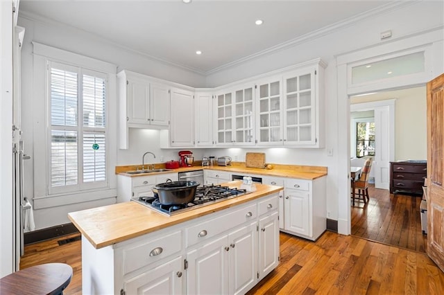 kitchen with sink, a kitchen island, light wood-type flooring, white cabinets, and appliances with stainless steel finishes