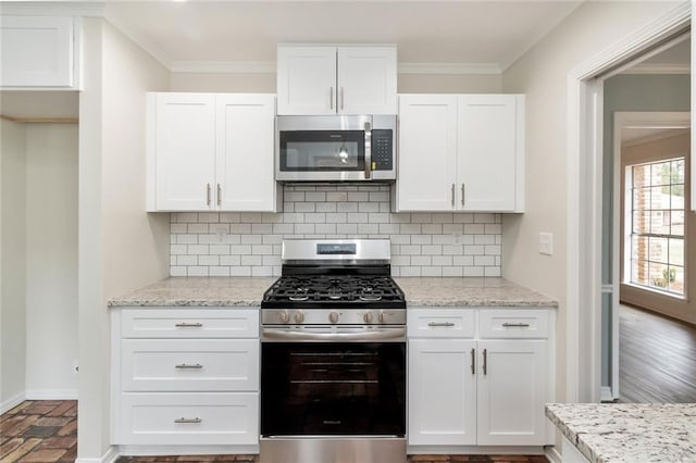 kitchen with white cabinets, ornamental molding, stainless steel appliances, and tasteful backsplash