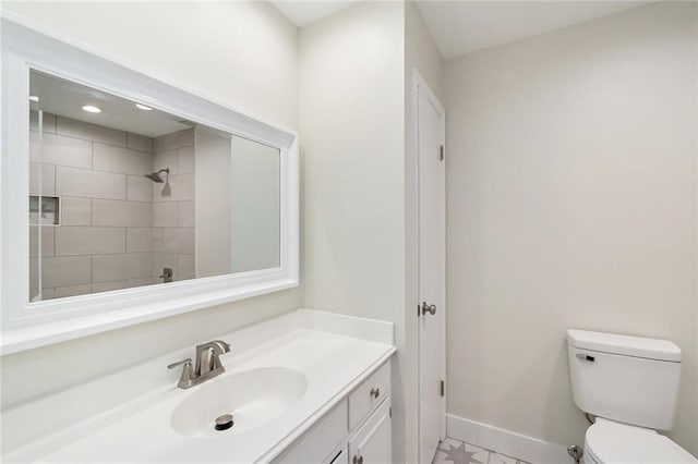 bathroom with vanity, toilet, and a tile shower