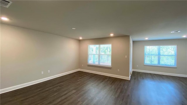 empty room with plenty of natural light and dark hardwood / wood-style flooring