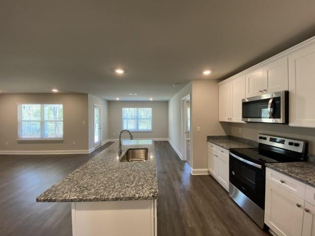 kitchen featuring sink, appliances with stainless steel finishes, a center island with sink, white cabinets, and stone countertops