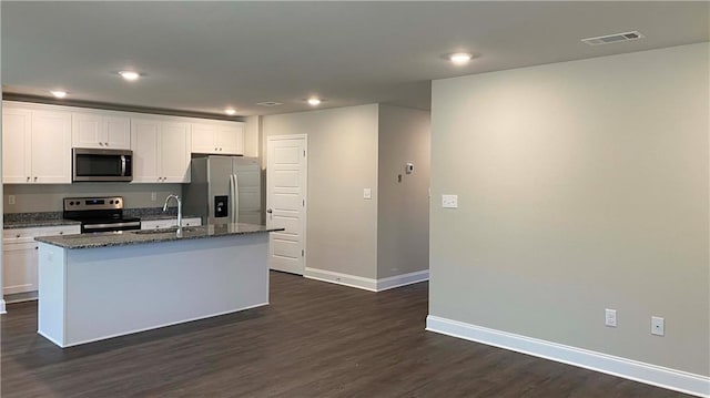 kitchen featuring sink, white cabinetry, stainless steel appliances, an island with sink, and dark stone counters