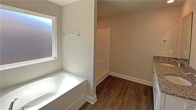 bathroom featuring vanity, a tub to relax in, plenty of natural light, and hardwood / wood-style floors