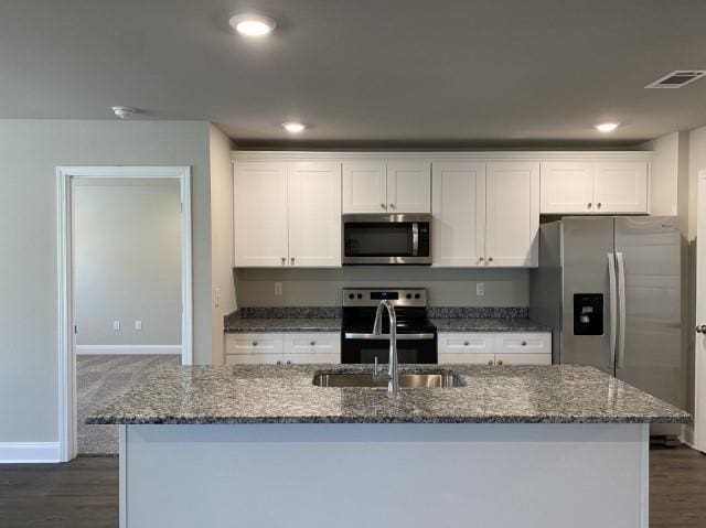 kitchen with sink, dark wood-type flooring, appliances with stainless steel finishes, white cabinetry, and an island with sink