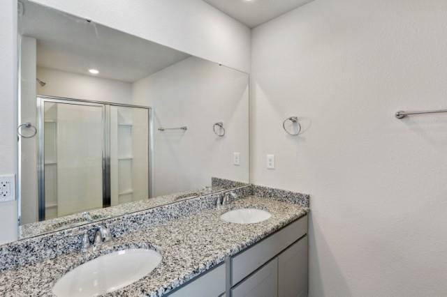 bathroom featuring a shower with door and vanity