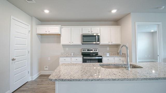 kitchen featuring light stone counters, stainless steel appliances, sink, and white cabinets