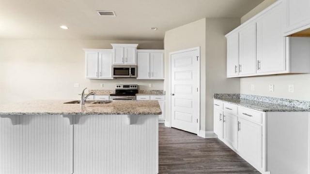 kitchen featuring appliances with stainless steel finishes, light stone countertops, sink, and white cabinets