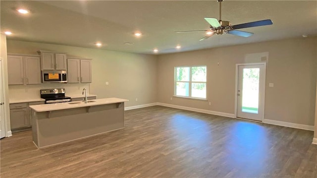 kitchen featuring sink, gray cabinetry, stainless steel appliances, an island with sink, and dark hardwood / wood-style flooring