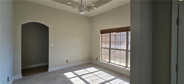 2509 Hedgerow Dr, Mobile, AL 36695 - empty room featuring baseboards, arched walkways, a chandelier, and light wood-style flooring