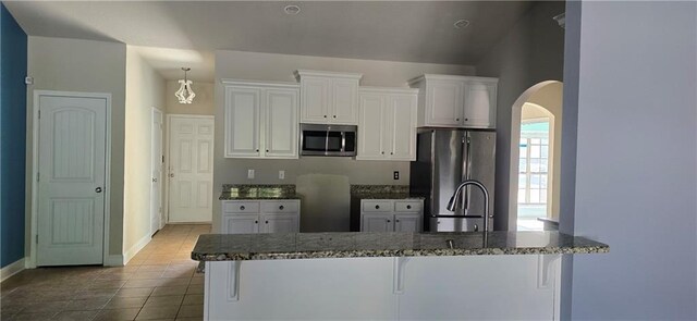 2509 Hedgerow Dr, Mobile, AL 36695 - kitchen featuring white cabinets, arched walkways, dark stone countertops, baseboards, and appliances with stainless steel finishes