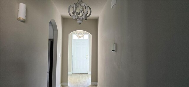 2509 Hedgerow Dr, Mobile, AL 36695 - hall featuring arched walkways, baseboards, an inviting chandelier, and light wood-style floors