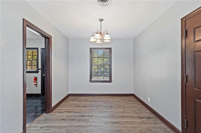 unfurnished room with hardwood / wood-style flooring and an inviting chandelier