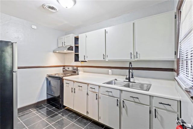 kitchen with a wealth of natural light, white cabinetry, sink, stainless steel fridge, and electric range