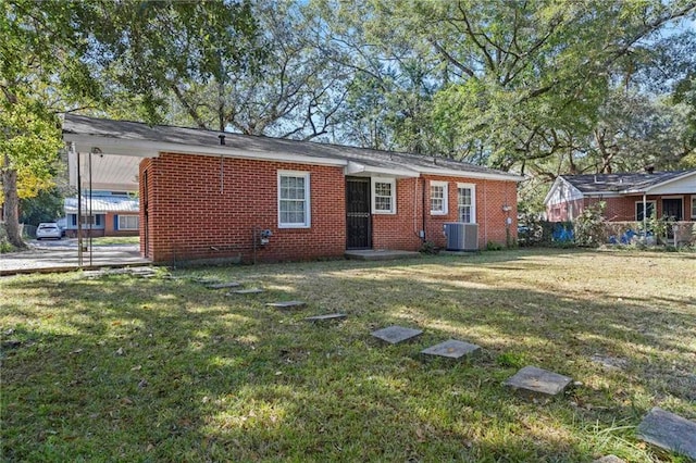 back of property with central AC unit and a lawn