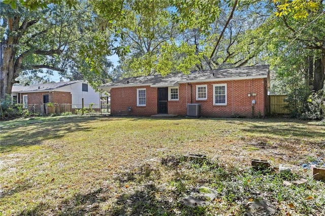 back of house with central AC unit and a yard