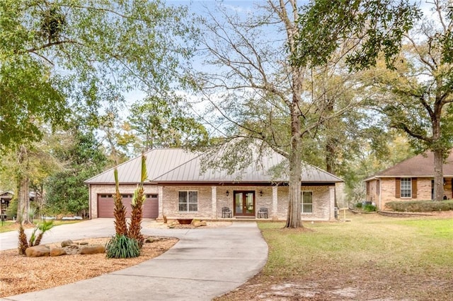 view of front of house featuring a front yard, driveway, an attached garage, french doors, and brick siding