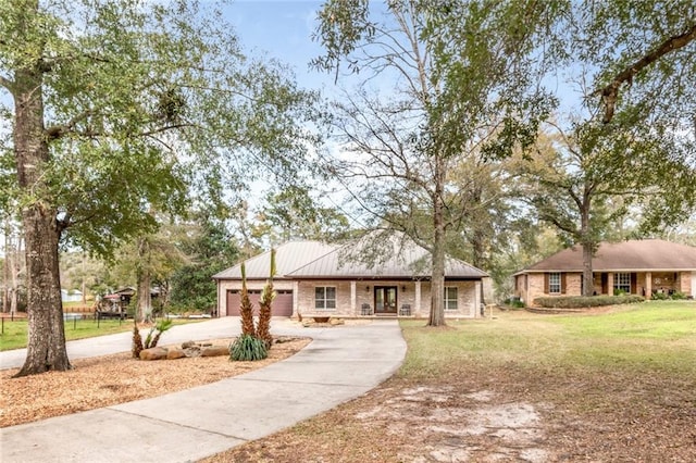 ranch-style home with a front yard, a porch, an attached garage, concrete driveway, and metal roof