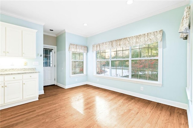 unfurnished dining area with light hardwood / wood-style floors, plenty of natural light, and ornamental molding